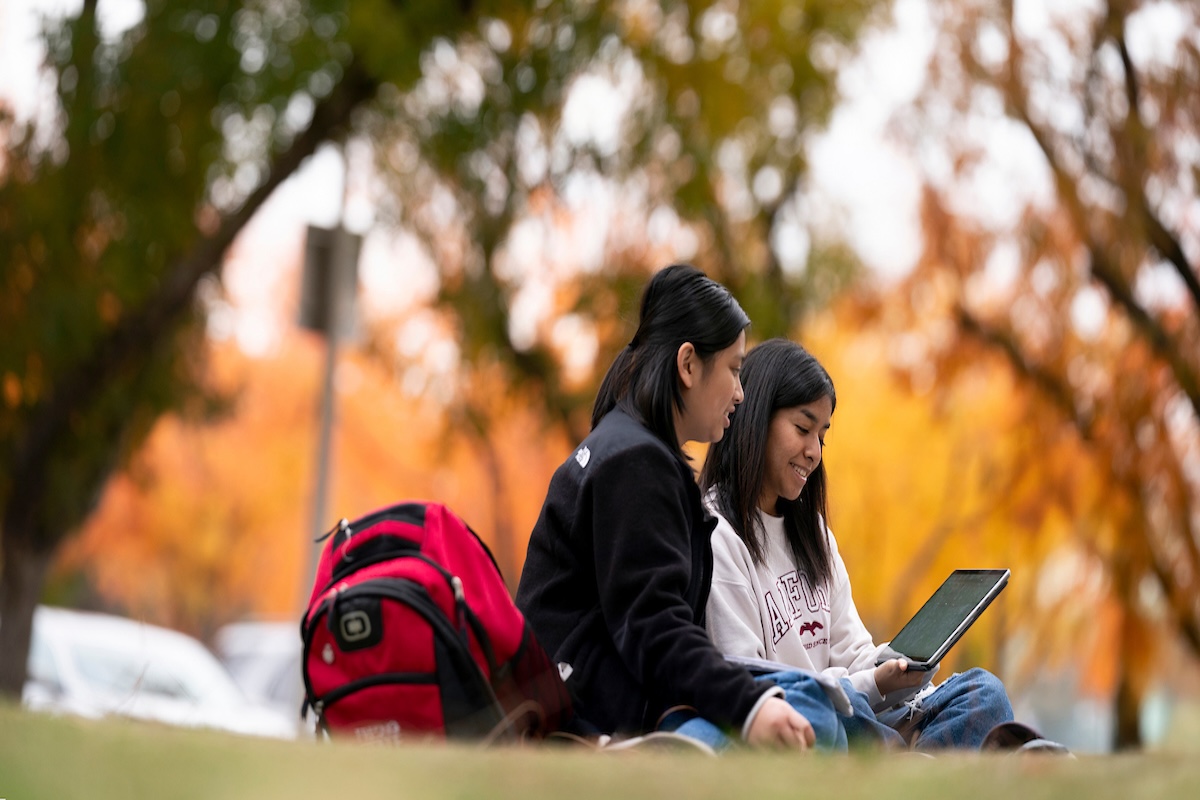 two students sitting and looking at laptop
